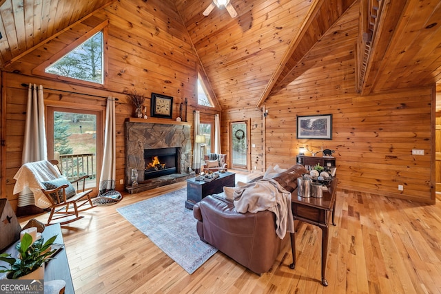 living room with a fireplace, light hardwood / wood-style floors, wood walls, and wooden ceiling