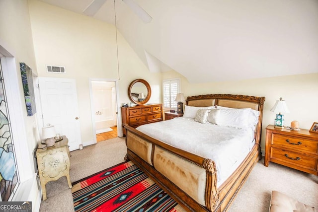 bedroom with lofted ceiling, connected bathroom, light carpet, and ceiling fan