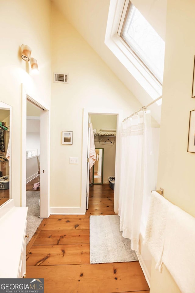 bathroom featuring vanity, hardwood / wood-style floors, a skylight, and high vaulted ceiling