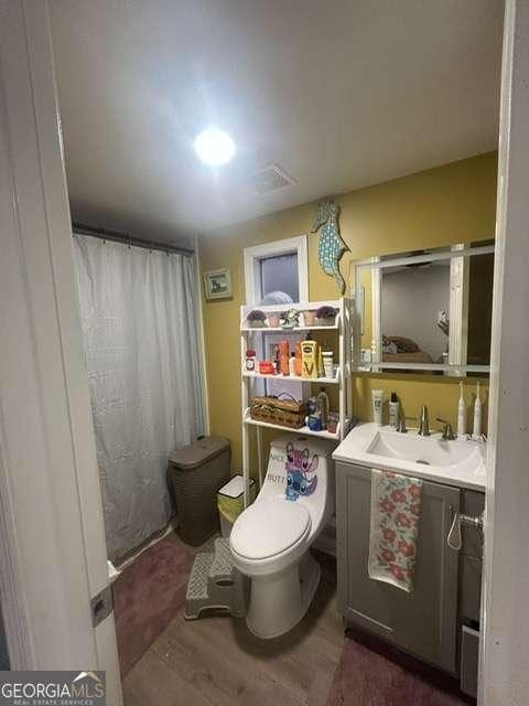 bathroom with a shower with curtain, vanity, hardwood / wood-style floors, and toilet