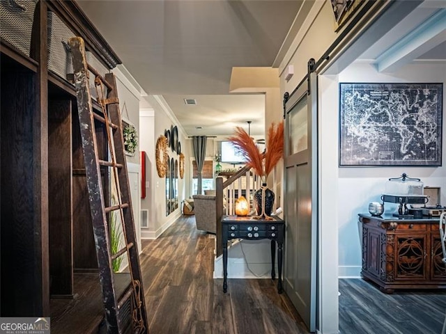 hallway featuring dark hardwood / wood-style floors, ornamental molding, and a barn door