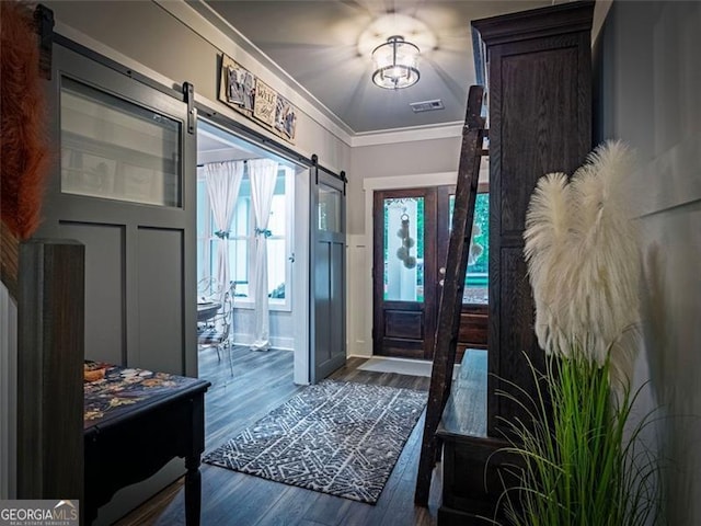 foyer entrance featuring ornamental molding, a barn door, and dark hardwood / wood-style floors