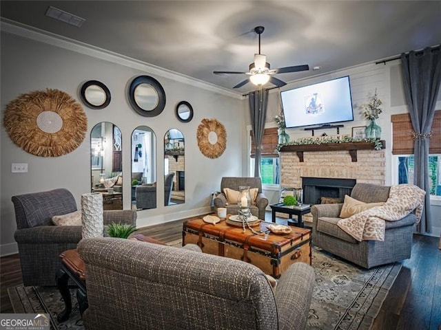 living room with a fireplace, ornamental molding, dark hardwood / wood-style floors, and ceiling fan