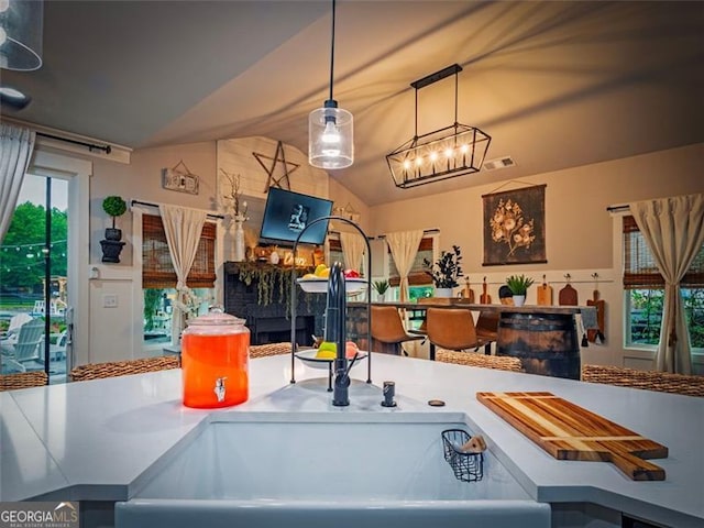 interior space with lofted ceiling, decorative light fixtures, and sink