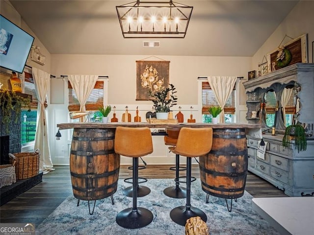 bar featuring dark hardwood / wood-style flooring, a brick fireplace, and decorative light fixtures