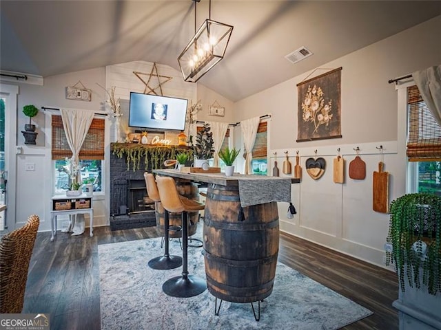 dining space with a fireplace, lofted ceiling, and dark hardwood / wood-style flooring