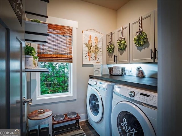 laundry area with dark wood-type flooring, cabinets, and washer and clothes dryer