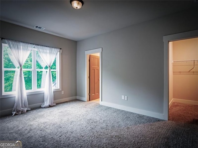 unfurnished bedroom featuring a spacious closet and carpet