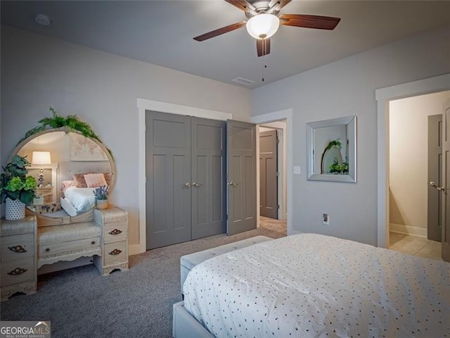 bedroom featuring light colored carpet, a closet, and ceiling fan