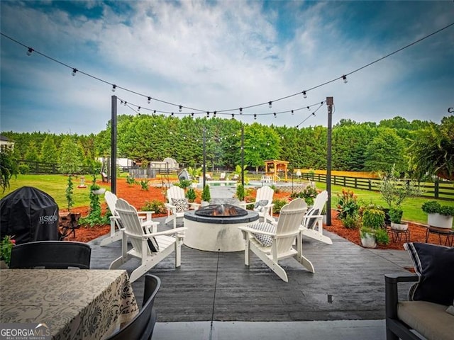 view of patio with a wooden deck, a fire pit, grilling area, and a playground