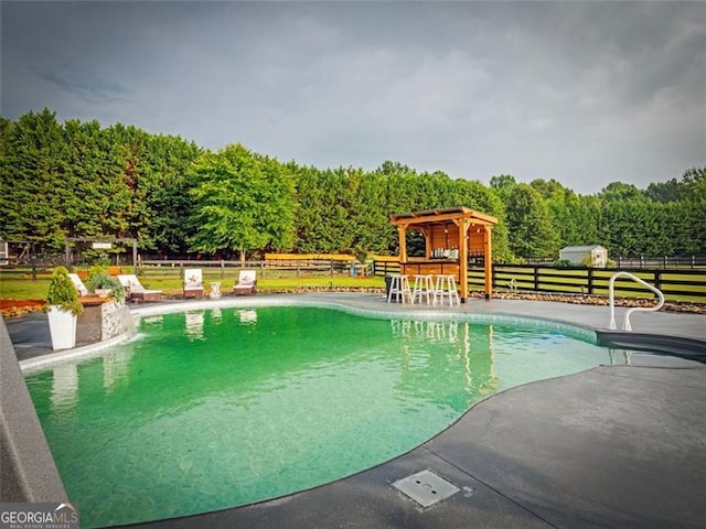 view of pool with an outdoor bar and a patio