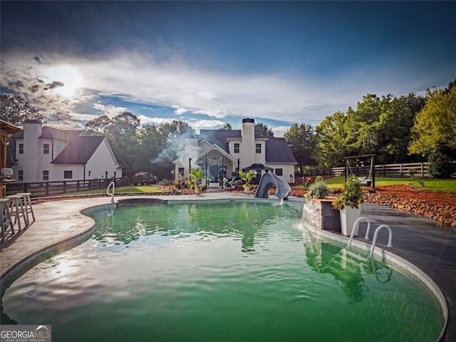 view of pool with a water slide and a patio area