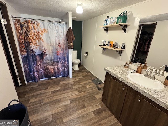 bathroom with vanity, hardwood / wood-style flooring, toilet, and a textured ceiling