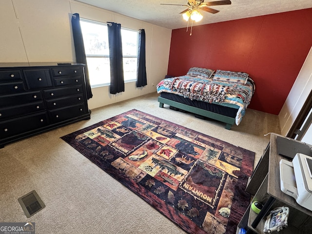 carpeted bedroom with ceiling fan and a textured ceiling