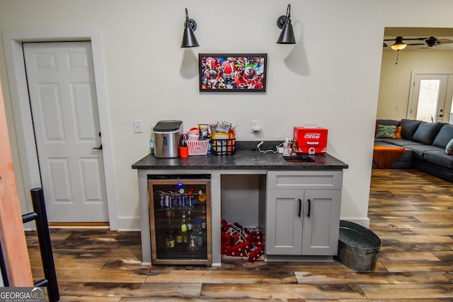 bar featuring gray cabinets, beverage cooler, and dark hardwood / wood-style flooring