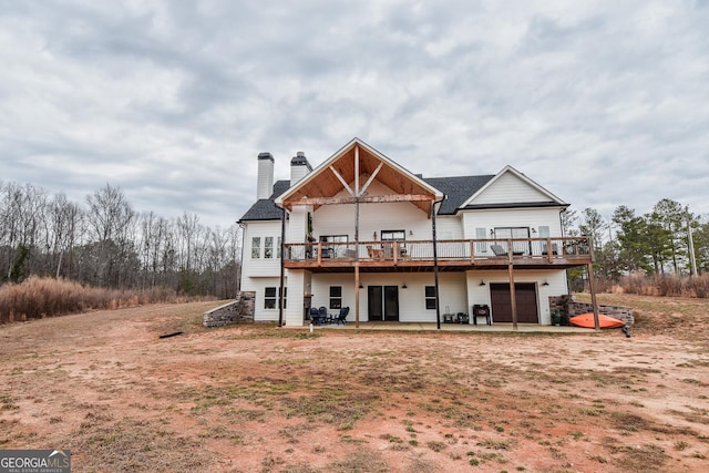 back of property featuring a garage, a deck, and a patio area