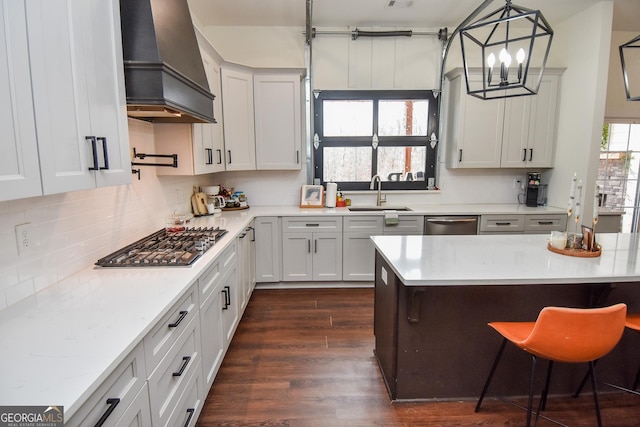 kitchen featuring premium range hood, appliances with stainless steel finishes, pendant lighting, sink, and white cabinets