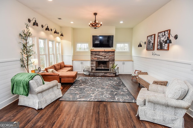 living room with dark hardwood / wood-style floors, an inviting chandelier, and a fireplace