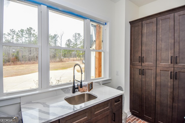 interior space with light stone counters, sink, and dark brown cabinetry