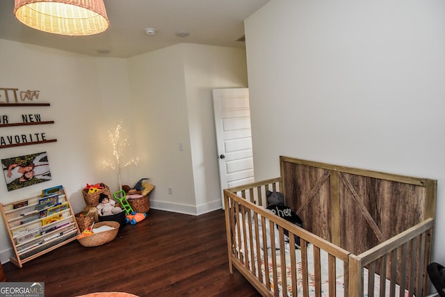 bedroom with a nursery area and dark wood-type flooring