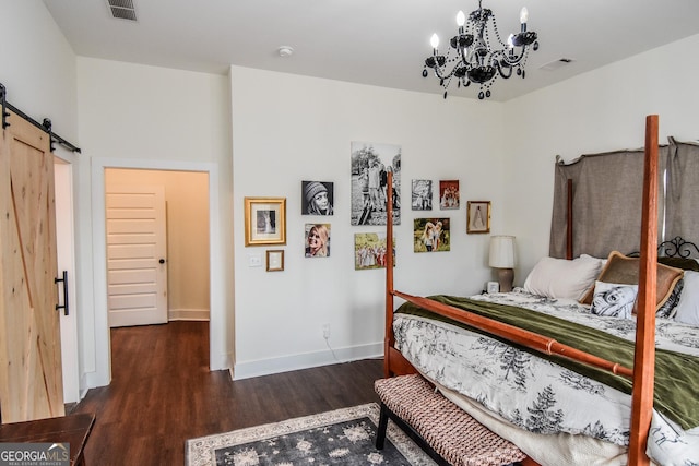 bedroom with dark hardwood / wood-style floors, a barn door, and a chandelier