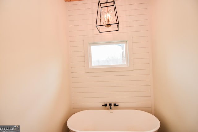 bathroom featuring a bath and wooden walls