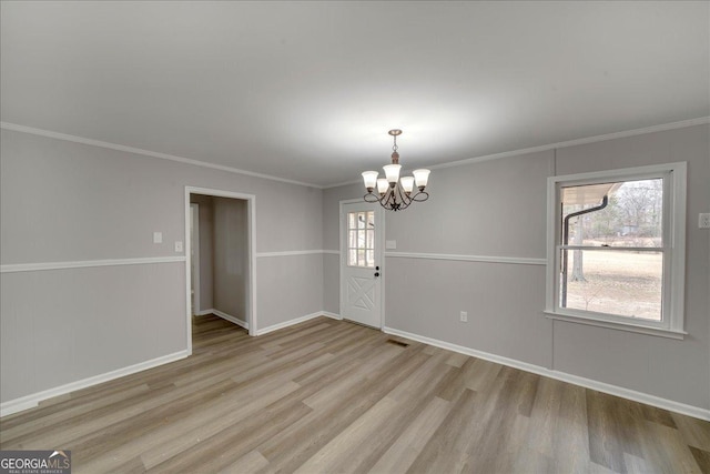 spare room featuring an inviting chandelier, light hardwood / wood-style flooring, and ornamental molding