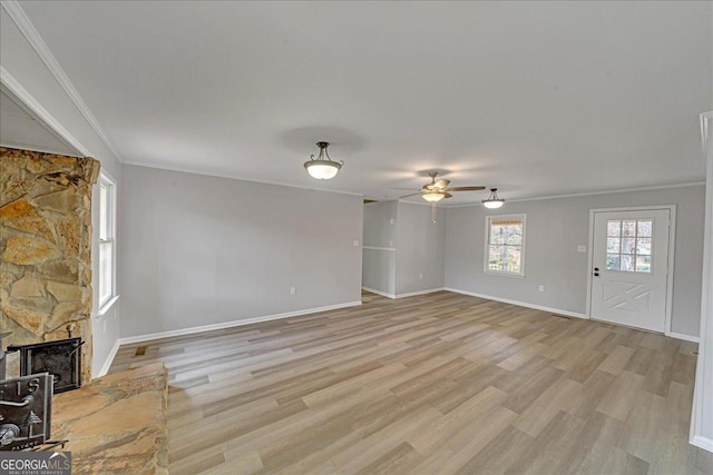 unfurnished living room featuring crown molding, ceiling fan, a fireplace, and light hardwood / wood-style floors