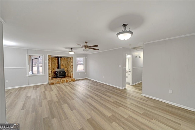 unfurnished living room featuring crown molding, a wood stove, ceiling fan, and light hardwood / wood-style floors