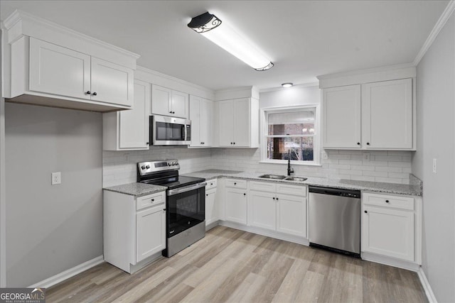 kitchen with stainless steel appliances, sink, white cabinets, and light hardwood / wood-style floors