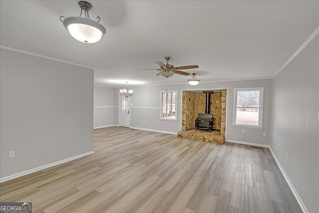 unfurnished living room with ornamental molding, a healthy amount of sunlight, light hardwood / wood-style floors, and a wood stove