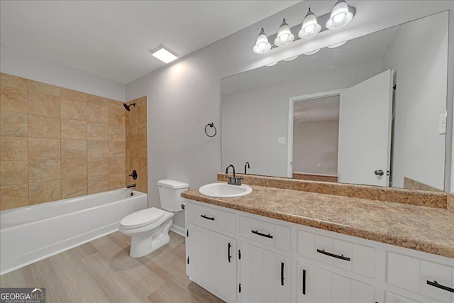 full bathroom featuring hardwood / wood-style flooring, vanity, tiled shower / bath combo, and toilet