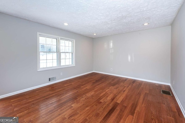 unfurnished room featuring dark hardwood / wood-style flooring and a textured ceiling