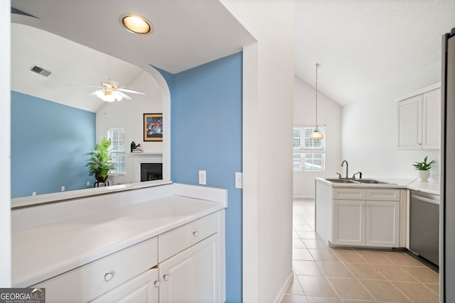 kitchen with sink, light tile patterned floors, white cabinets, decorative light fixtures, and stainless steel dishwasher