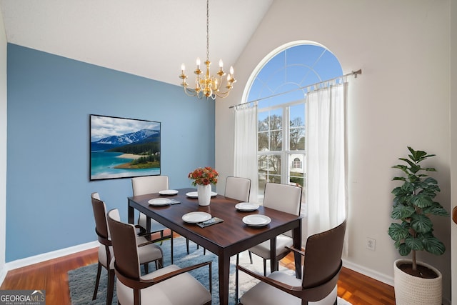 dining room featuring dark wood-type flooring, high vaulted ceiling, and an inviting chandelier