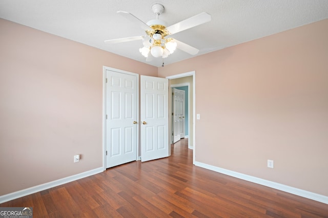 unfurnished bedroom with a closet, dark hardwood / wood-style floors, and ceiling fan