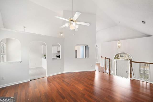 unfurnished living room with wood-type flooring, ceiling fan with notable chandelier, and high vaulted ceiling