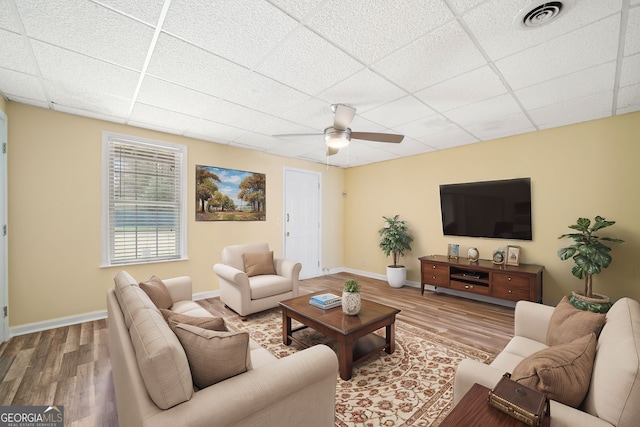 living room featuring a drop ceiling, hardwood / wood-style floors, and ceiling fan