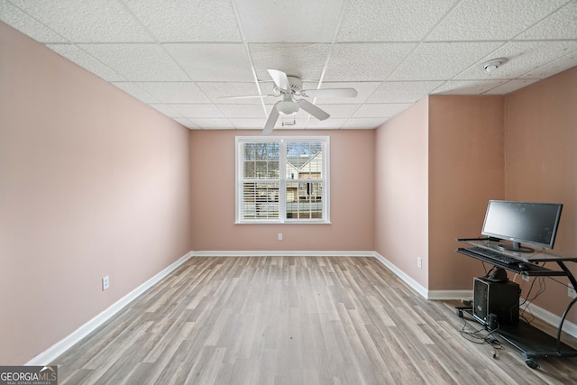 unfurnished office with a paneled ceiling, ceiling fan, and light hardwood / wood-style flooring