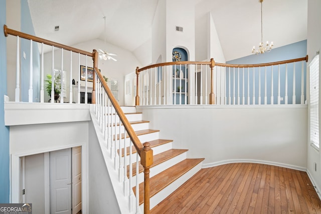 stairway featuring ceiling fan with notable chandelier, high vaulted ceiling, and hardwood / wood-style flooring