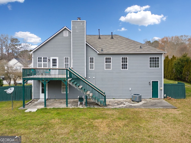 rear view of property featuring cooling unit, a wooden deck, a patio area, and a lawn