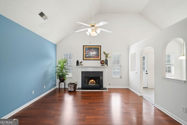 unfurnished living room with a healthy amount of sunlight, high vaulted ceiling, dark hardwood / wood-style floors, and ceiling fan