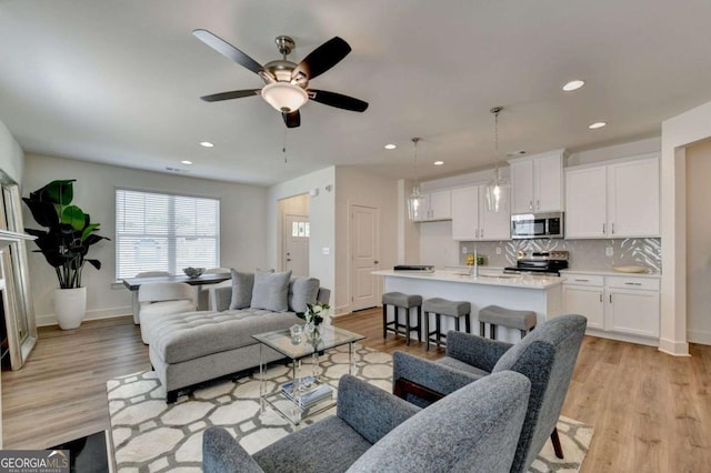 living room featuring ceiling fan and light hardwood / wood-style flooring