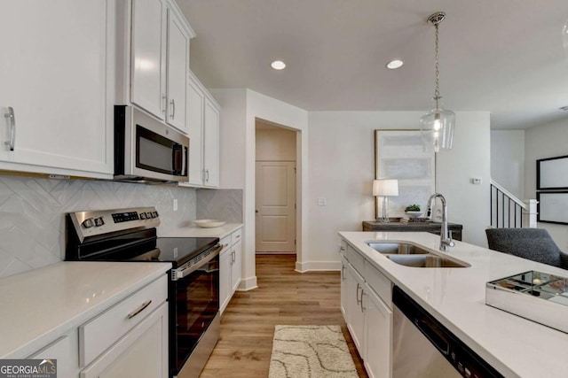 kitchen with tasteful backsplash, sink, white cabinets, hanging light fixtures, and stainless steel appliances