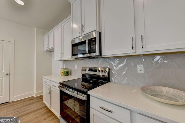 kitchen featuring stainless steel appliances, white cabinetry, light hardwood / wood-style floors, and decorative backsplash