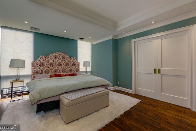 bedroom featuring visible vents, crown molding, baseboards, and wood finished floors