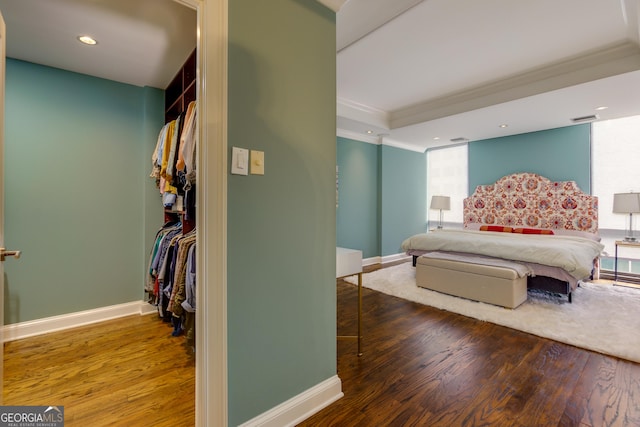 bedroom featuring baseboards, wood finished floors, visible vents, and ornamental molding