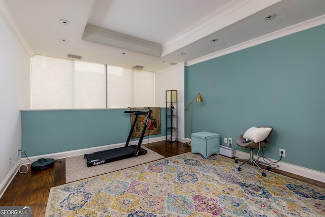 workout room featuring wood finished floors, visible vents, a raised ceiling, and ornamental molding