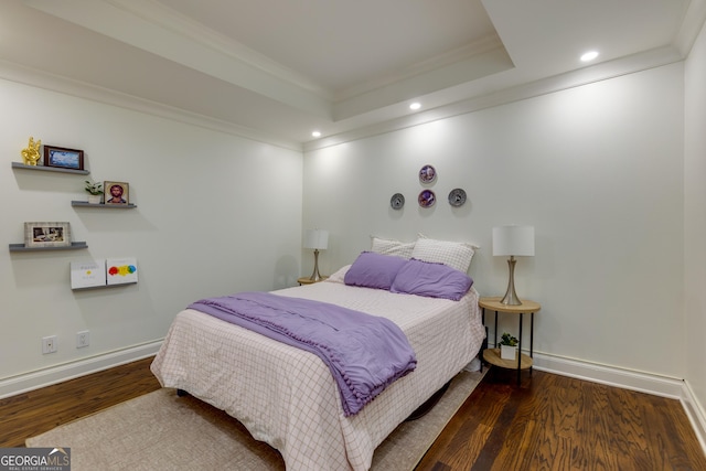 bedroom with crown molding, wood finished floors, baseboards, and a tray ceiling