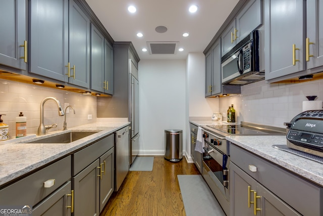 kitchen featuring stainless steel dishwasher, light stone countertops, dark wood-style flooring, and a sink